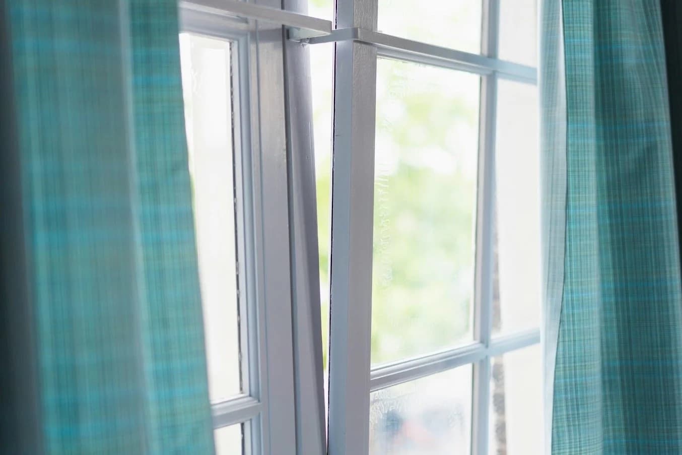 Sunlight shining through clean window panes with teal curtains